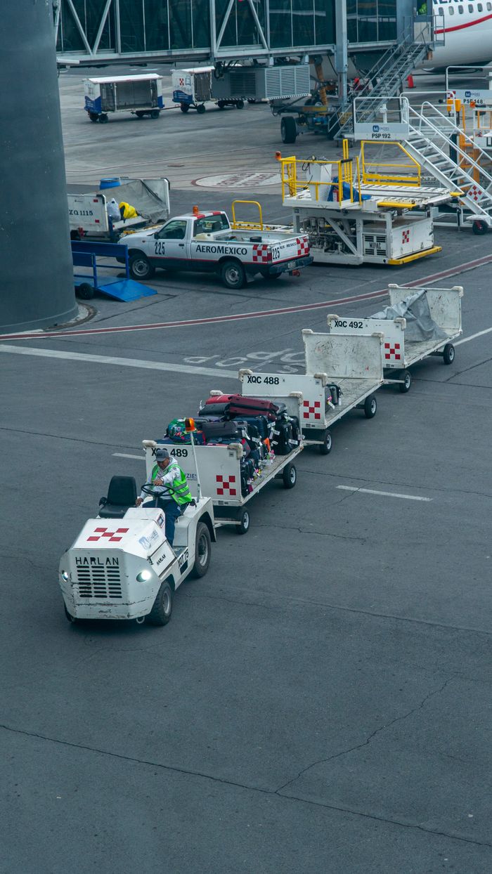 Crafting Captivating Headlines: Your awesome post title goes here Ground crew managing luggage on tarmac with baggage carts and vehicle at airport.