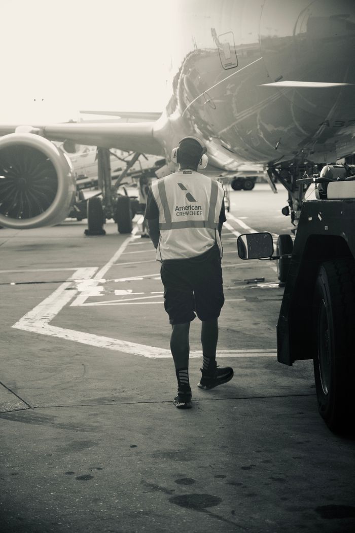Mastering the First Impression: Your intriguing post title goes here Ground crew member in safety vest walks near airplane at airport terminal
